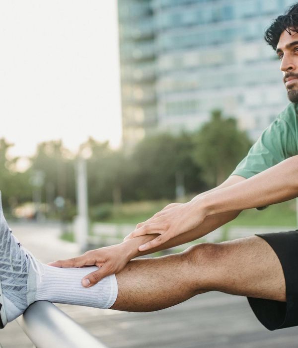 Smiling person stretching outdoors in a park at sunrise.